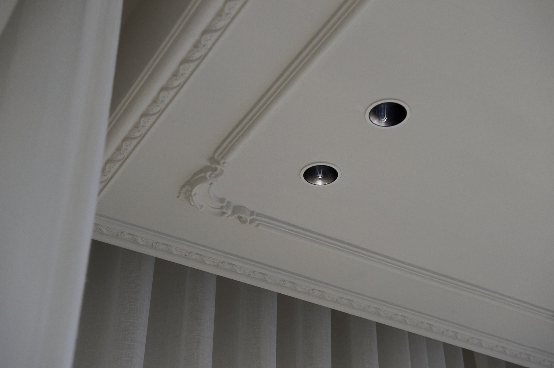 Cornici da parete decorative applicate al soffitto, che mettono in risalto i faretti da incasso e le proporzioni del soffitto.