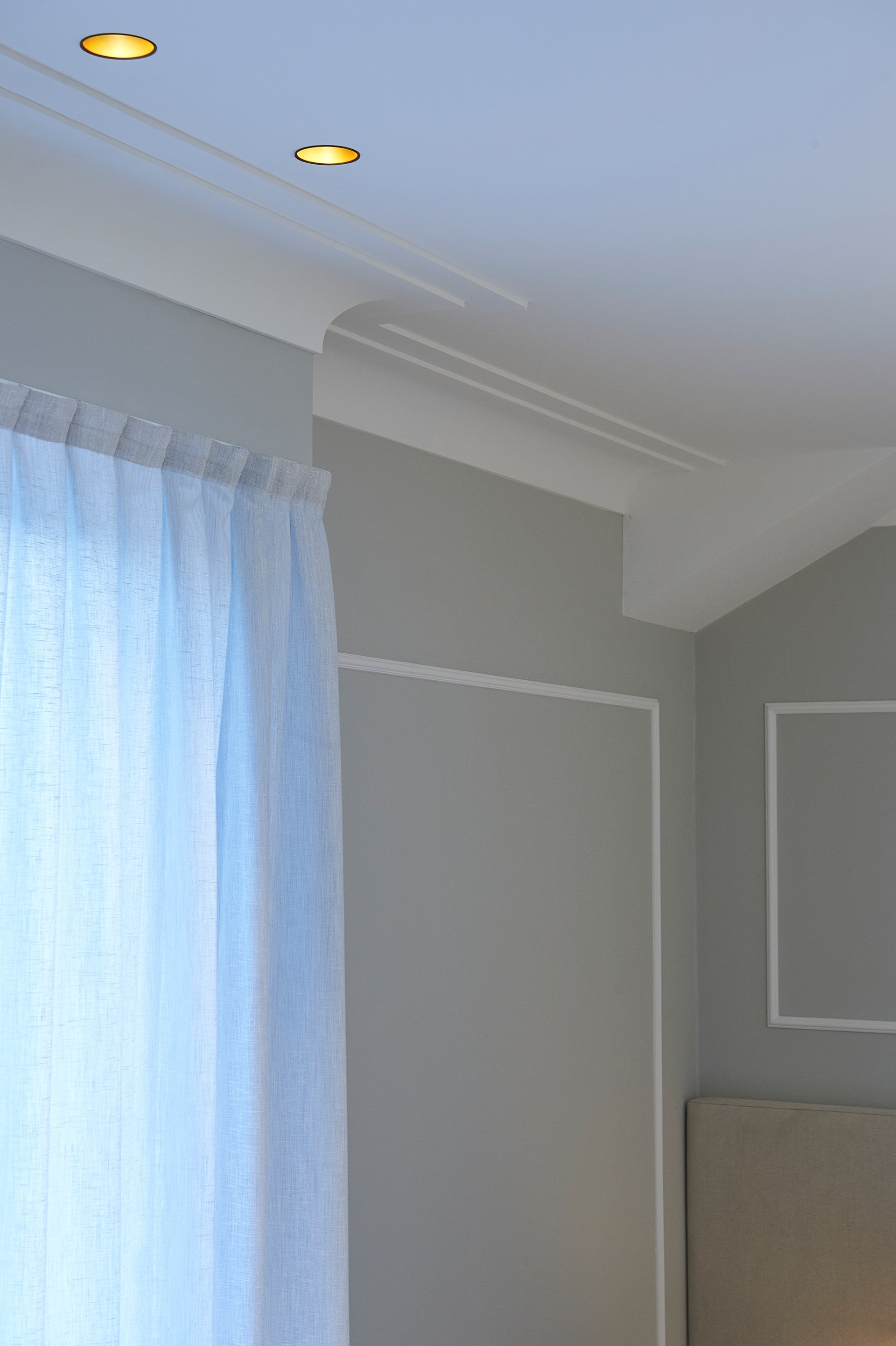 Cornici minimaliste che definiscono il passaggio tra parete e soffitto in un ambiente moderno.